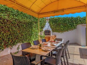 An outdoor dining area with a table set for two, surrounded by wicker chairs, under a yellow canopy. - Libertos V4 - VIP Properties by Interhome (Albufeira)