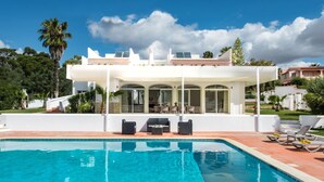 A modern house with a swimming pool, outdoor seating, and a covered patio area.