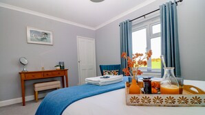 Une chambre à coucher comprenant un lit, une table de chevet, un bureau, une chaise, une fenêtre avec des rideaux et un plateau avec des articles pour le petit-déjeuner.