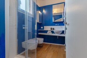Een douche, een bidet, handdoeken, toiletpapier