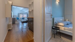 Een kamer met een bed, een stoel, een bureau en uitzicht op een buitenruimte.