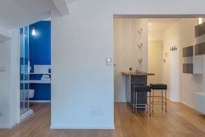 A modern kitchen with a bar area, wooden flooring, and a blue accent wall.