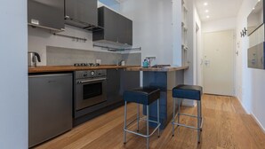 Een moderne keuken met roestvrijstalen apparatuur, houten aanrechtbladen en twee blauwe barkrukken.