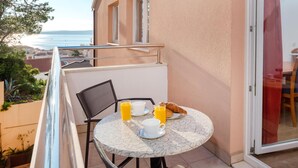 A balcony with a table set for breakfast, overlooking a coastal view. - Awesome apartment in Baska Voda (Baska Voda)