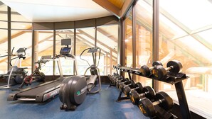 Un gimnasio con cintas de correr, elípticas y un estante de mancuernas.