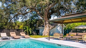 Une piscine avec des chaises longues et un espace de détente abrité.