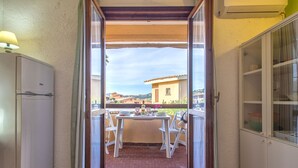 A small balcony with a table and chairs, a refrigerator, and a cabinet. - F4 - F2, Baia de Bahas by Interhome (Golfo di Marinella)