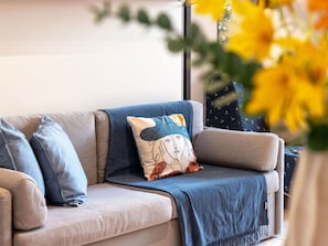 Un canapé agrémenté d’un plaid bleu et de coussins décoratifs.