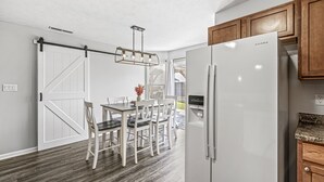 Une cuisine avec un réfrigérateur blanc, des armoires en bois et un coin repas comprenant une table et des chaises.