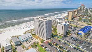 Un hôtel situé sur la côte, composé de plusieurs immeubles de grande hauteur, avec une plage et un parking.