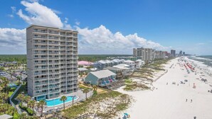Un hôtel de grande hauteur doté de nombreux balcons, d’une piscine et situé en bord de mer.