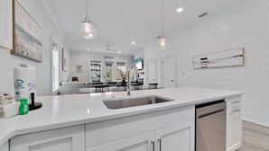A modern kitchen with white cabinetry, a stainless steel sink, and pendant lighting.
