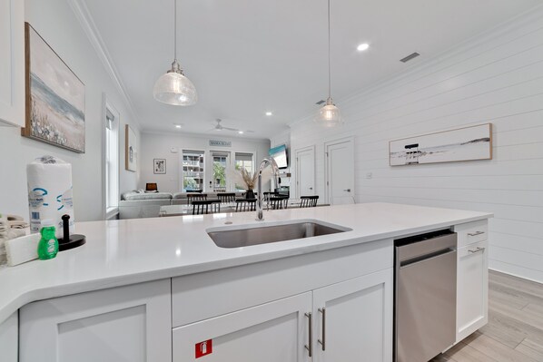 A modern kitchen with white cabinetry, a stainless steel sink, and pendant lighting.