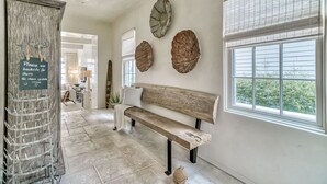 Un couloir avec un banc en bois, un porte-chaussures fixé au mur et trois grandes coquilles décoratives.