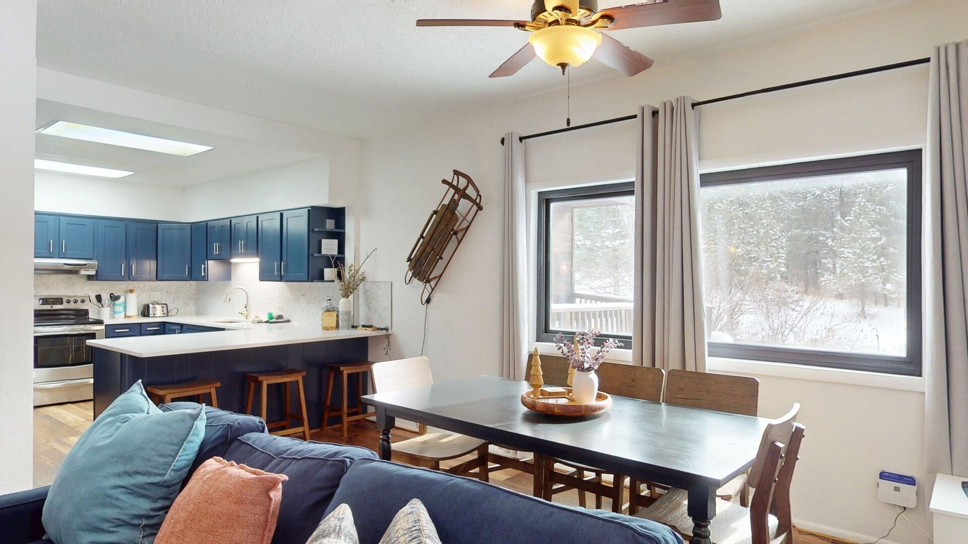 A modern kitchen with dark blue cabinets, a central island, and a dining area with a table and chairs.