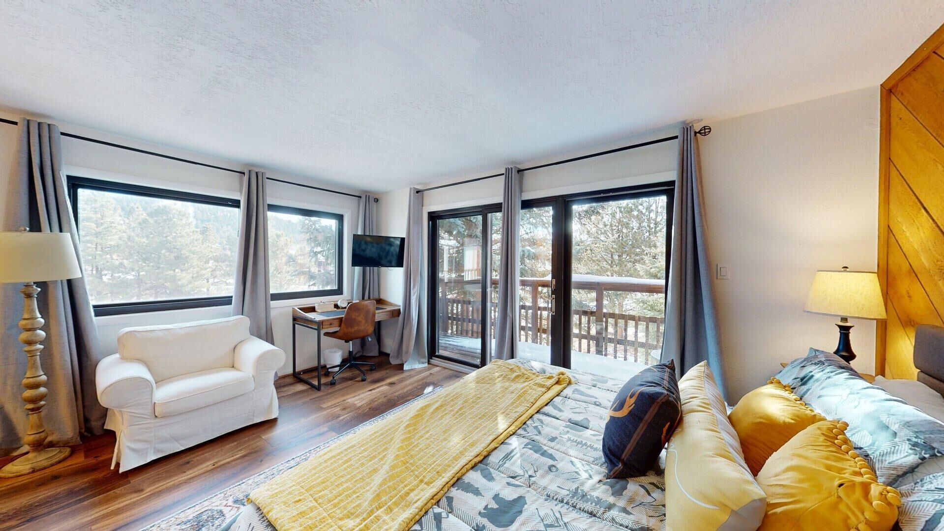 Una habitación de hotel moderna con una cama grande, un sofá, un escritorio y un televisor.