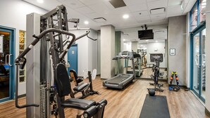 Un gimnasio con máquinas de cardio, equipo de levantamiento de pesas y una caminadora.
