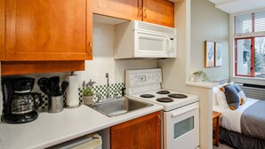 Una cocina compacta con armarios de madera, microondas, estufa y cafetera.