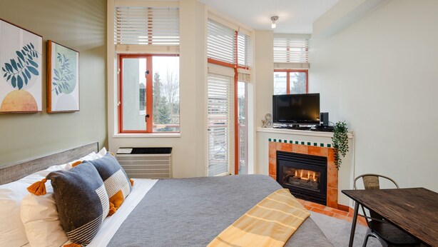 Un dormitorio con cama, televisión, chimenea y zona de comedor.
