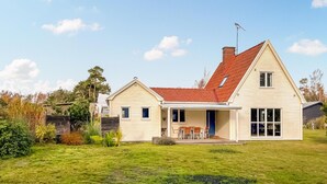 A two-story house with a red roof, a chimney, and a large front porch with outdoor seating. - 4 bedroom cozy home in Beddingestrand (Beddingestrand)