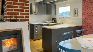 A modern kitchen with a central island, grey cabinets, a brick wall, and a fireplace. - 4 bedroom cozy home in Beddingestrand (Beddingestrand)
