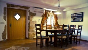 A dining area with a wooden table and chairs, a stone wall, and a door with a light fixture. - Villa Mediterana (Kvarner - Kras) (Kras)