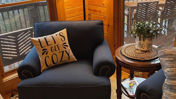 A cozy room with a blue armchair, a wooden floor, a lamp, and a view of trees through a window. - Gratitude View - It's cooler in the mountains! (Ararat)