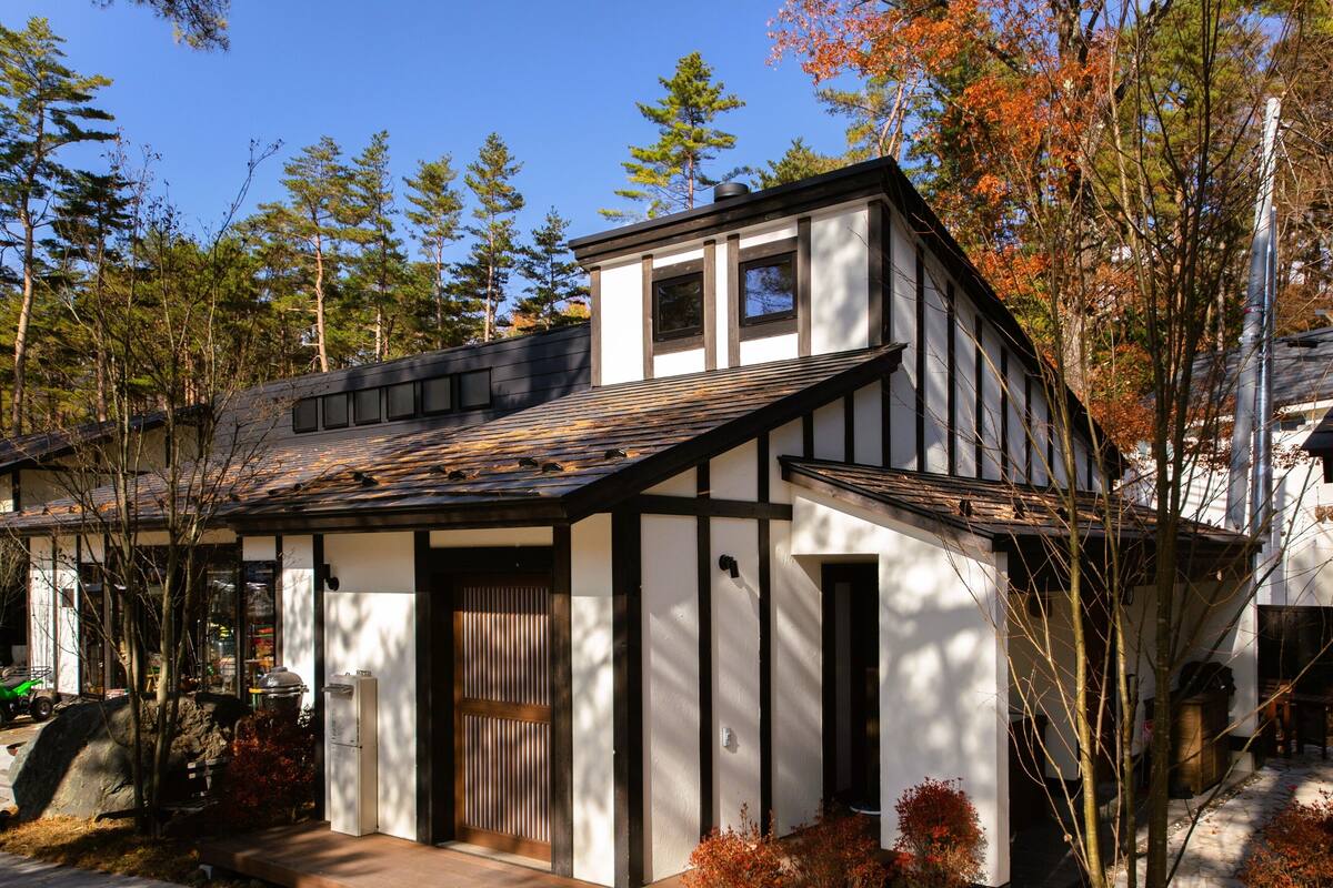 Une maison moderne avec un toit en pente, une porte d’entrée en bois et un petit porche.