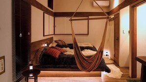 A room with a bed, a hanging chair, a small table, and a door. - Hanz Outdoor Resort (formerly Glamping Villa Hanz Kawaguchiko) (Fujikawaguchiko)