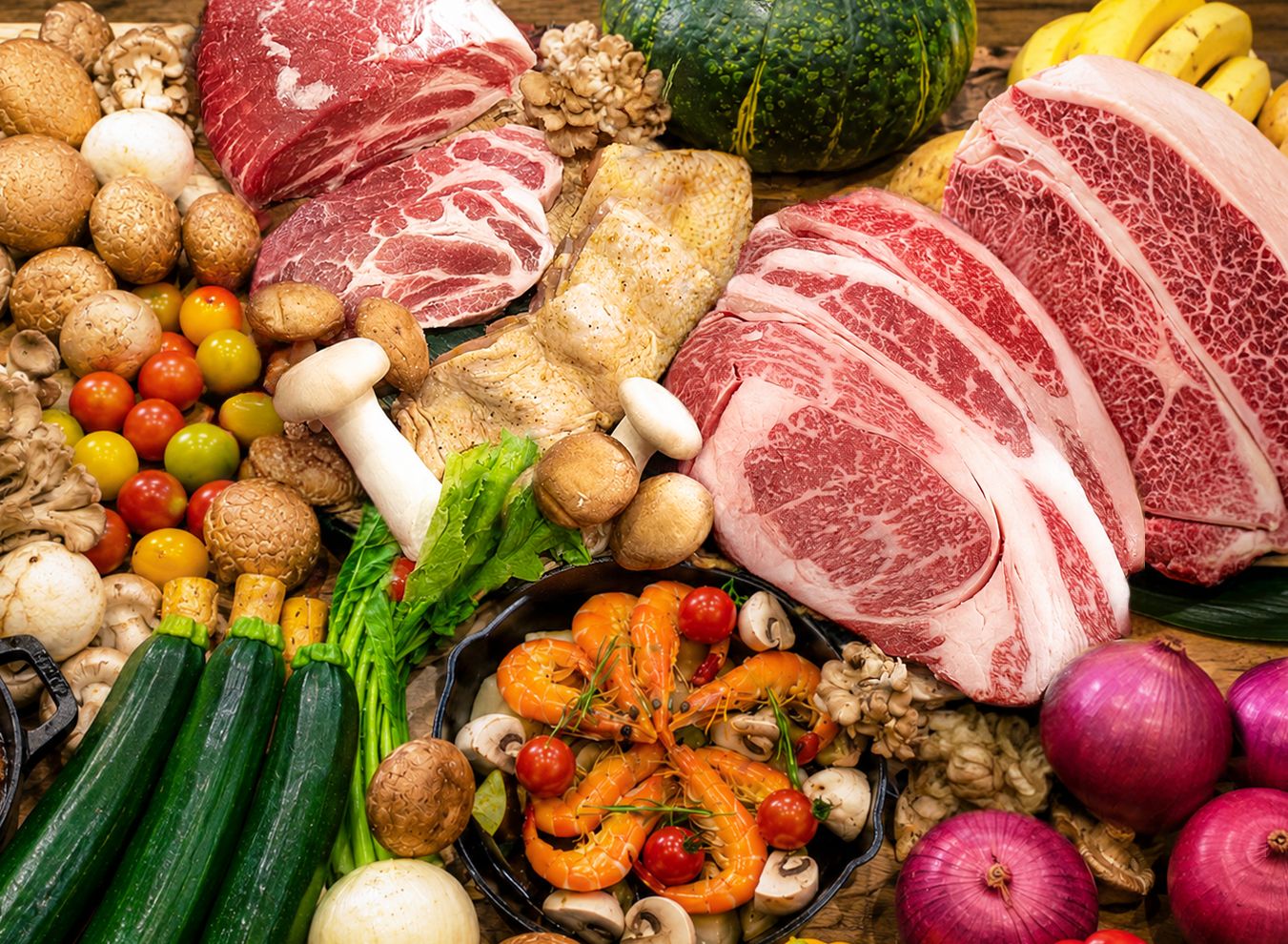 A variety of fresh produce and meats, including tomatoes, mushrooms, and different cuts of beef, arranged on a wooden surface.