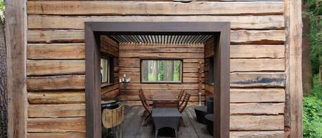 A log cabin with a central dining area featuring a table and chairs, surrounded by wooden walls and a window.