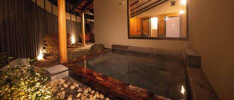 A traditional Japanese onsen with a wooden bench, a stone pathway, and a wooden fence.