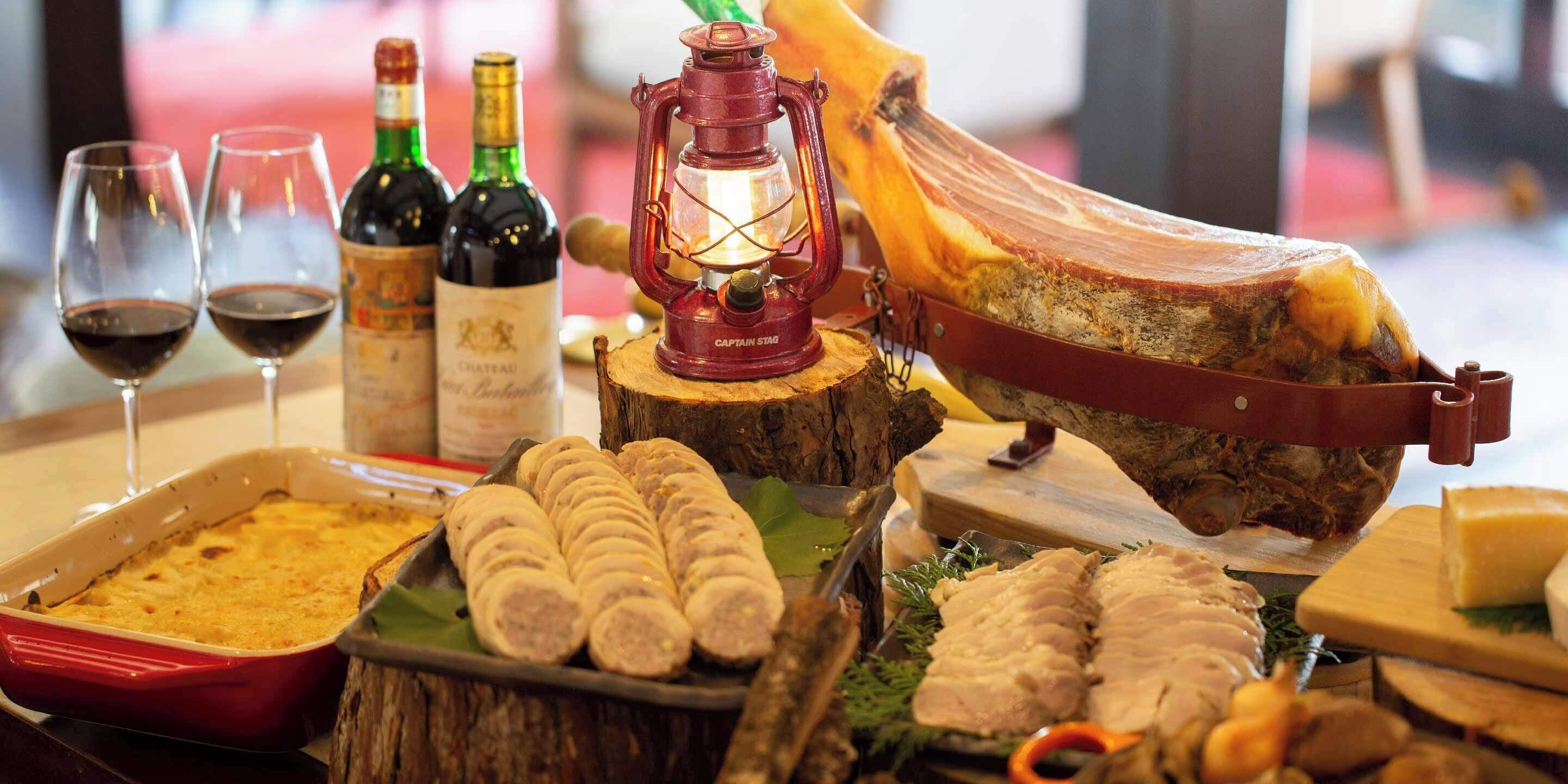 Una tabla de quesos y embutidos con distintos tipos de carne, queso y una botella de vino.