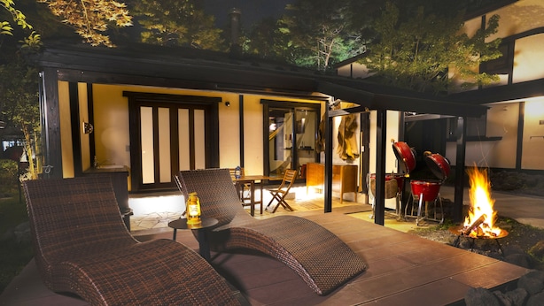 An outdoor patio with wicker lounge chairs, a table, and a fire pit. - Hanz Outdoor Resort (formerly Glamping Villa Hanz Kawaguchiko) (Fujikawaguchiko)