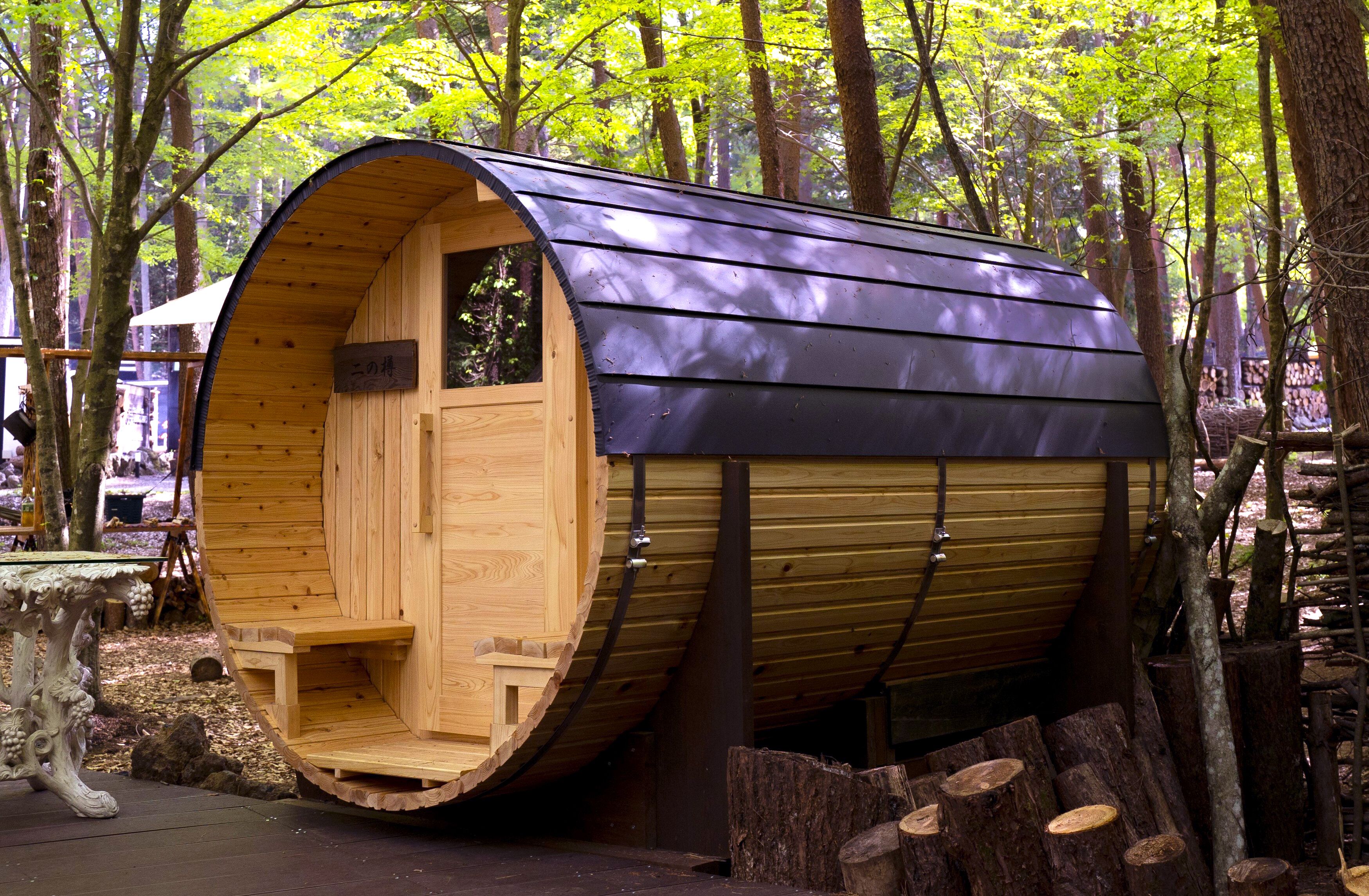 A wooden cabin with a curved roof, situated in a forest.