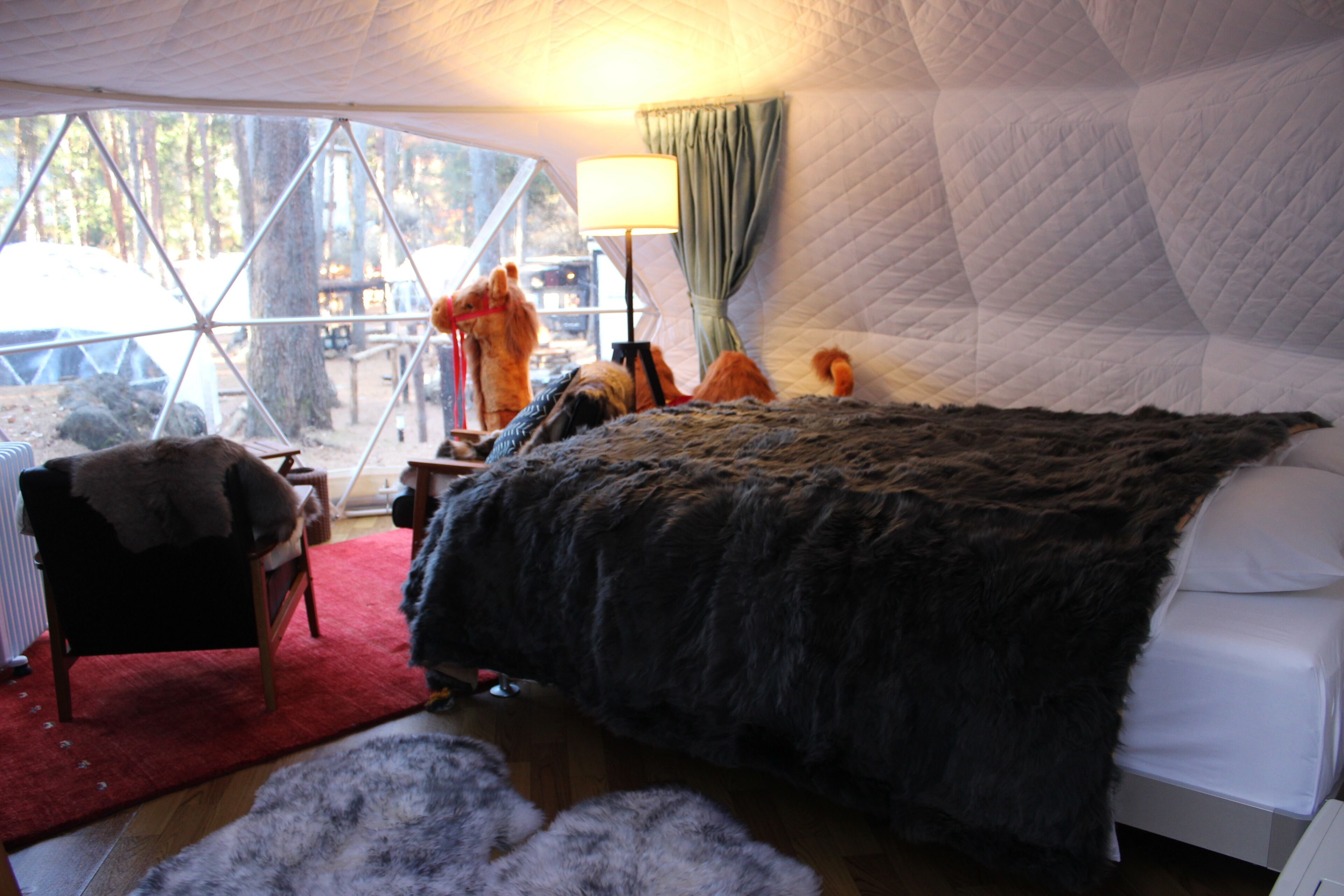A cozy room with a large bed, a chair, and a red rug.