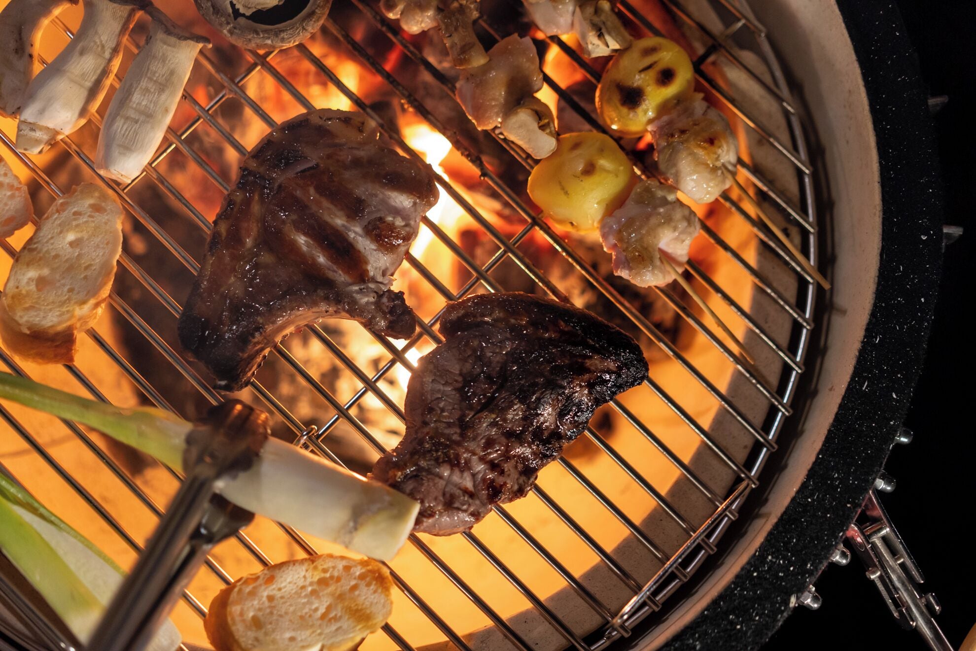 Een barbecue met vlees en groenten die worden gebakken.