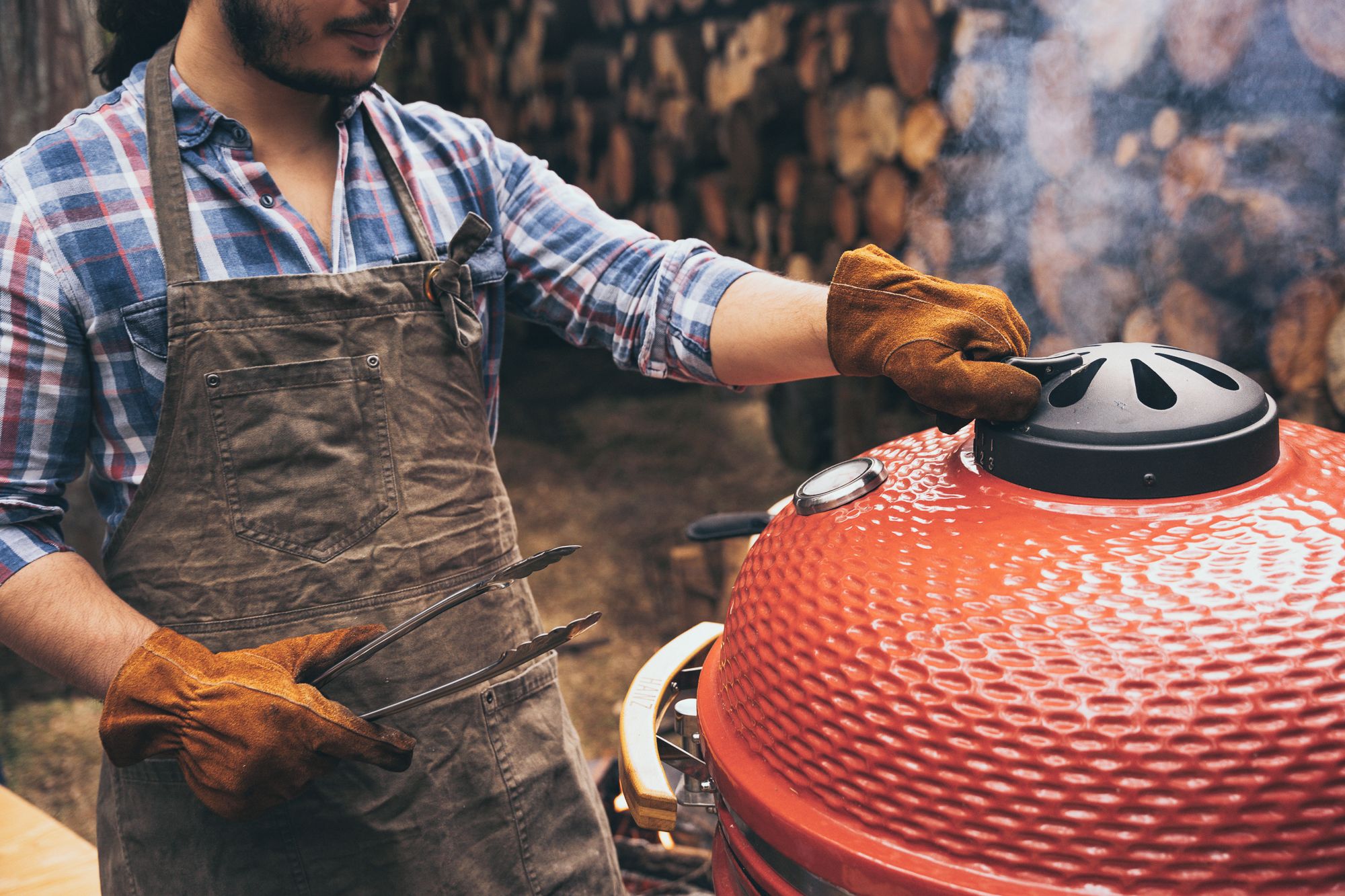 Une personne qui fait griller des aliments sur un barbecue rouge.