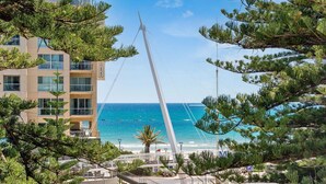 A coastal hotel with a prominent white tower, a beach view, and a parking area. - Sea the Views (Glenelg)