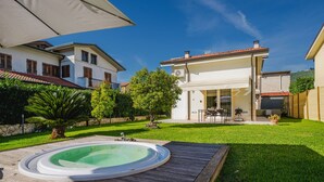 Ein Garten mit Swimmingpool, überdachter Terrasse und gepflegtem Rasen.