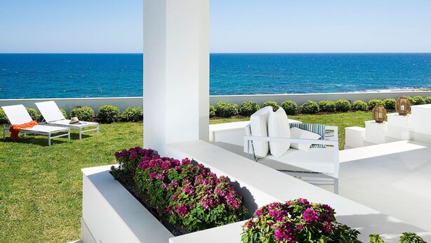 A modern outdoor seating area with white furniture and a view of the ocean.