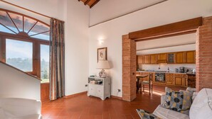 A spacious living area with a sofa, a small table with a lamp, and a view of a kitchen through an open doorway. - Stunning private villa with private pool, WIFI, A/C, TV, terrace, pets allowed and panoramic view (Greve In Chianti)