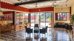 A spacious lobby with tiled flooring, multiple seating areas, ceiling fans, and large windows offering views of the outdoors.