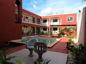 Ein Innenhof mit Swimmingpool, Kübelpflanzen und einem überdachten Sitzbereich.