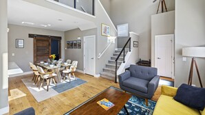 Un vaste espace de vie comprenant une table à manger, des canapés et un escalier.