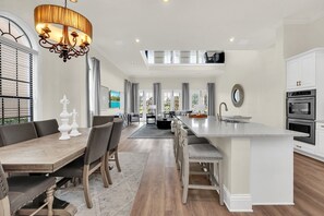 A spacious kitchen with a large island, white cabinetry, and modern appliances. - Golden Hideaway | 5BR, Private Pool, Lake View (Kissimmee)