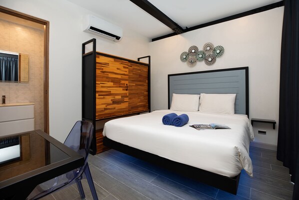 A modern hotel room with a wooden wardrobe, a bed with white linens, and a small table with a chair. - Innovative 12m Eco Pool Villa Sunset 1 (Rawai)