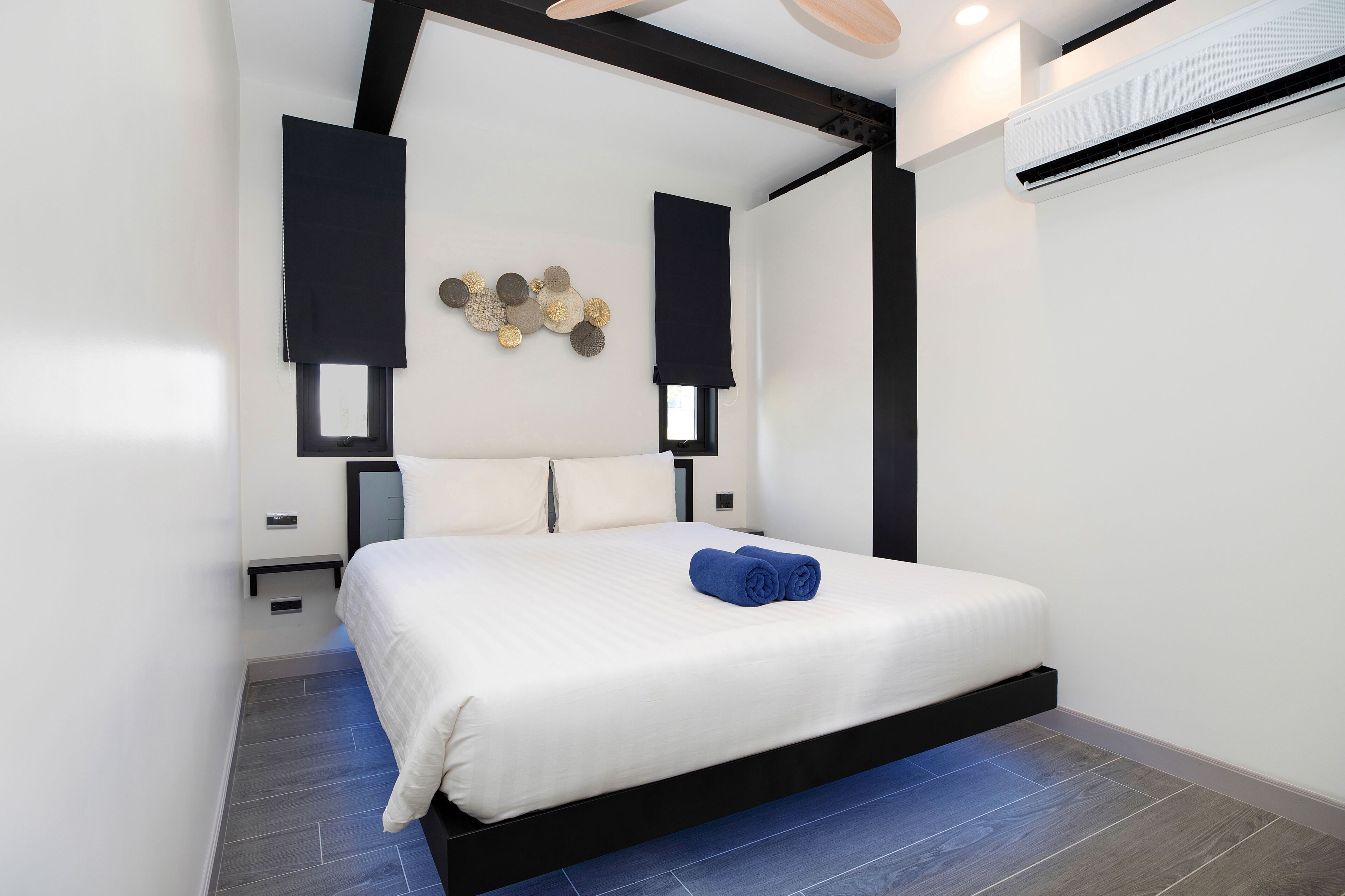 A modern bedroom with a large bed, black headboard, and white bedding.