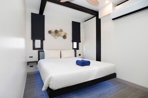 A modern bedroom with a large bed, black headboard, and white bedding. - Innovative 12m Eco Pool Villa Sunset 1 (Rawai)