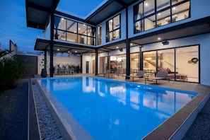 A modern house with a swimming pool, large windows, and a staircase leading to the upper floor. - Innovative 12m Eco Pool Villa Sunset 1 (Rawai)